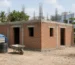 Single-storey house under construction in Coimbatore at lintel level with red brick walls, door and window openings and steel bars ready for the roof slab